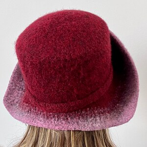 May include: A burgundy felt hat with a wide brim and a pink ombre effect on the brim.