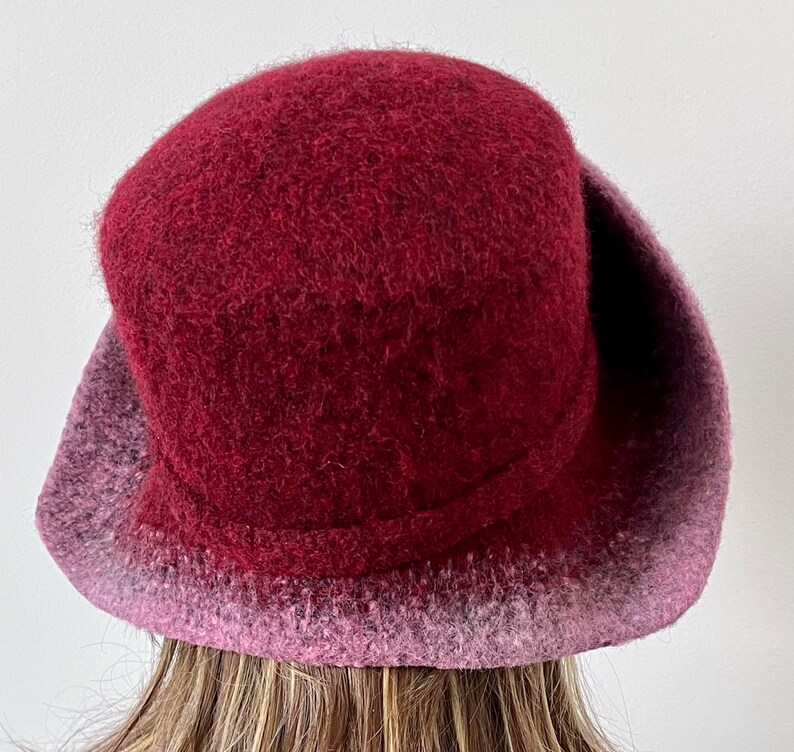 May include: A burgundy felt hat with a wide brim and a pink ombre effect on the brim.