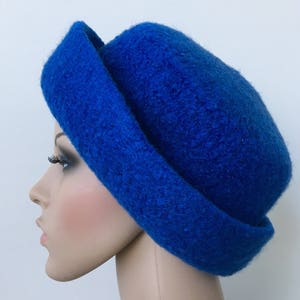 May include: A bright blue felt hat with a wide brim. The hat is folded over on one side, creating a unique and stylish look.