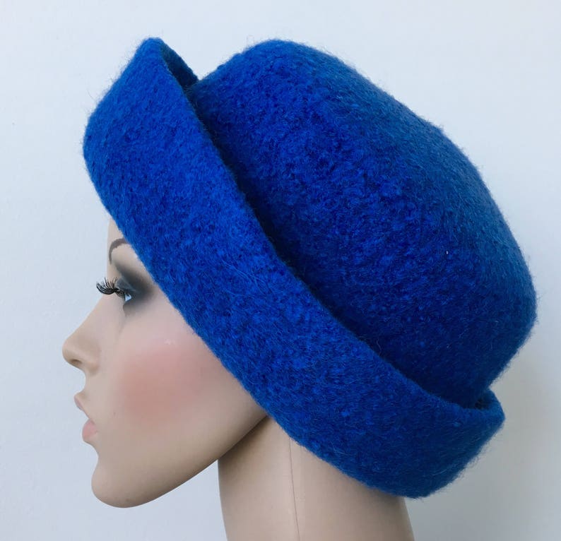 May include: A bright blue felt hat with a wide brim. The hat is folded over on one side, creating a unique and stylish look.