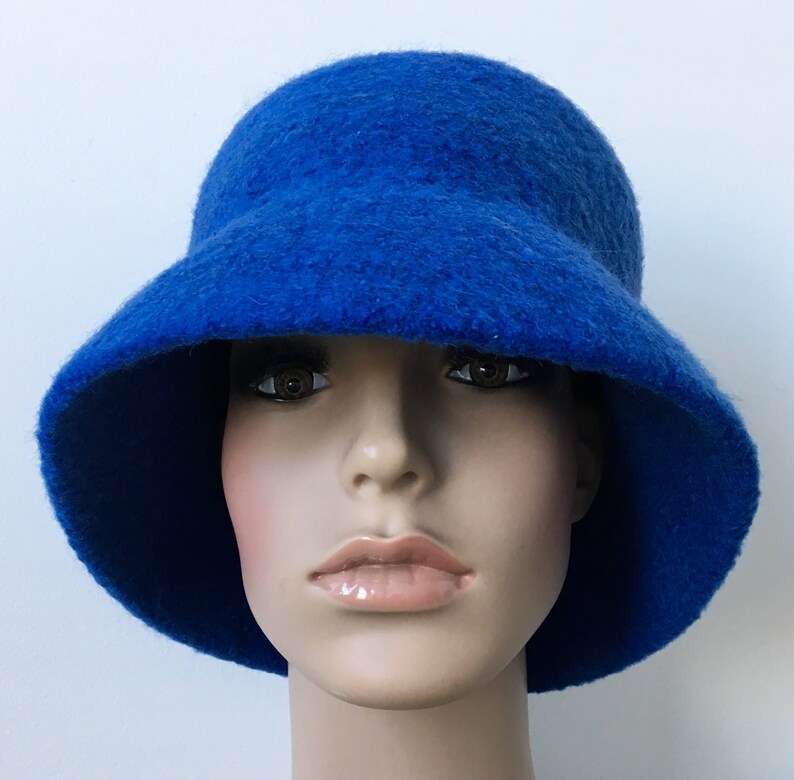 May include: A bright blue felt bucket hat with a wide brim. The hat is worn by a mannequin with a neutral expression.