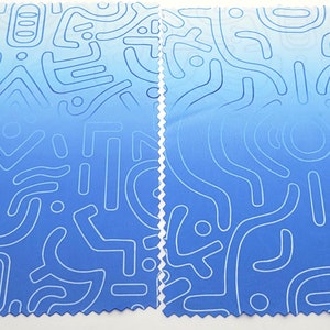 Puede incluir: Dos piezas de tela azul con un patr&oacute;n abstracto blanco. La tela tiene un degradado de azul claro a azul oscuro.