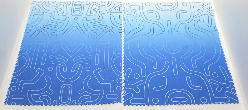 Puede incluir: Dos piezas de tela azul con un patr&oacute;n abstracto blanco. La tela tiene un degradado de azul claro a azul oscuro.