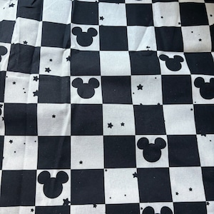 May include: Black and white checkered fabric with a repeating pattern of Mickey Mouse heads and small white stars.