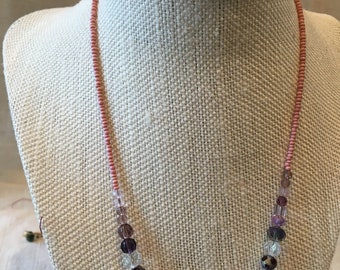 A sparkling necklace featuring assorted Swarovski crystals in shades of pink and purple .