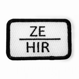 以下が含まれることがあります： 黒い刺繍で「ZE」が線の上に、「HIR」が線の下に書かれた白い長方形のパッチ