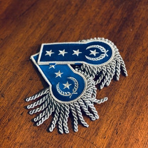 May include: Two blue shoulder boards with silver fringe and embroidered stars and a laurel wreath.