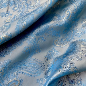 May include: Blue fabric with a white paisley pattern. The fabric is folded and has a soft, textured surface.