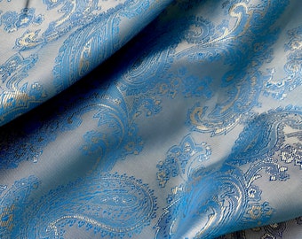 May include: Blue fabric with a white paisley pattern. The fabric is folded and has a soft, textured surface.