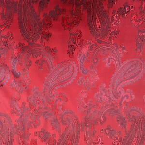 May include: Red fabric with a paisley pattern. The paisley pattern is in a darker shade of red and black.