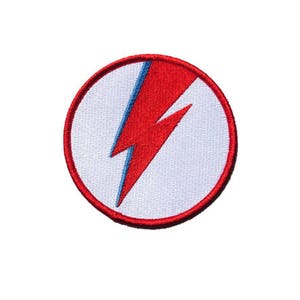 Op de afbeelding: Een witte cirkel met een rood bliksemontwerp. De bliksem heeft een blauwe omtrek.