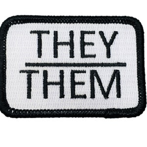 May include: White embroidered patch with black stitching. The patch reads "THEY/THEM" in all capital letters.