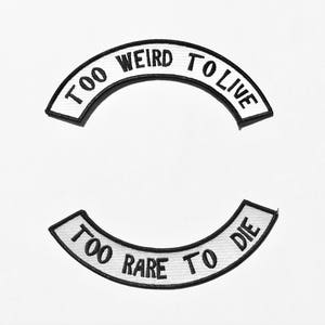 Könnte beinhalten: Zwei schwarz-weiße, gestickte Aufnäher mit gebogenen Designs. Der obere Aufnäher lautet "TOO WEIRD TO LIVE" und der untere Aufnäher lautet "TOO RARE TO DIE". Die Aufnäher befinden sich auf weißem Hintergrund.