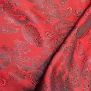 May include: Red fabric with a black paisley pattern. The fabric is folded in half, showing the pattern on both sides.