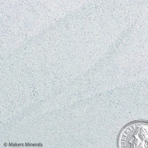 May include: A close-up of a light blue, textured surface with a silver US coin on the bottom right corner. The coin has the word "LIBERTY" printed on it.