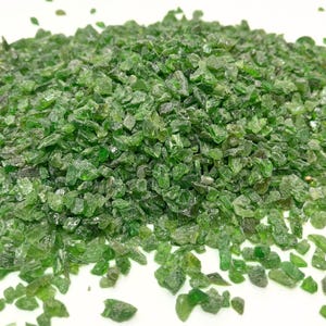 Könnte beinhalten: Ein Haufen kleiner, grüner, grob geschliffener Edelsteine. Die Edelsteine sind auf einer weißen Oberfläche verstreut.