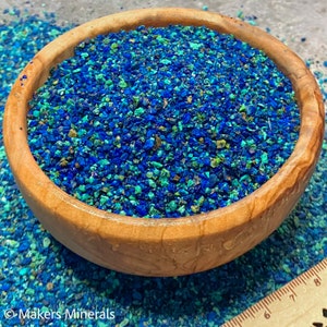 May include: A wooden bowl filled with small, blue and green mineral chips. The chips are a mix of turquoise and azurite.
