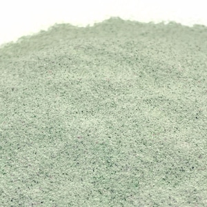May include: A close-up of a pile of light green powder. The powder is fine and has a slightly grainy texture.