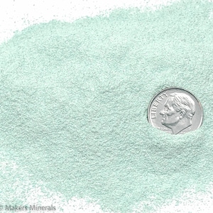 Può includere: Primo piano di un mucchio di polvere fine, verde chiaro, con un dime americano per il confronto delle dimensioni. La moneta mostra il profilo di Franklin D. Roosevelt e la parola "Liberty". La polvere ha una consistenza leggermente granulosa.