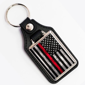 May include: Black leather keychain with a silver metal frame featuring a thin red line American flag design.
