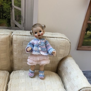 Dolls house 1.12th baby/toddler doll - comprising of: knitted cardigan, socks and hand made skirt