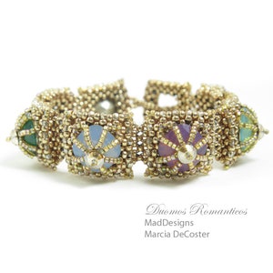 Könnte beinhalten: Ein goldfarbenes Perlenarmband mit vier quadratischen Fächern, die jeweils einen andersfarbigen Edelstein enthalten. Die Edelsteine sind blau, lila, grün und hellgrün. Das Armband heißt "Duomos Romantics" von MadDesigns Marcia DeCoster.