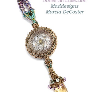 Könnte beinhalten: Eine handgefertigte Halskette aus der Bohemian Collection. Die Halskette hat einen großen, runden Anhänger mit silberfarbenem Design, umgeben von goldfarbenen Perlen. Ein tropfenförmiger, bernsteinfarbener Kristall hängt vom Anhänger. Hergestellt von Maddesigns, Marcia DeCoster.