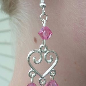 May include: Silver heart-shaped dangle earrings with pink crystal accents.