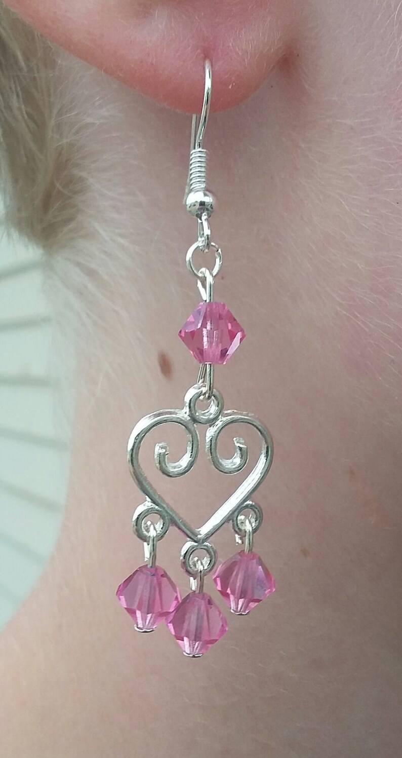 May include: Silver heart-shaped dangle earrings with pink crystal accents.