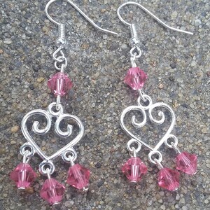 May include: Silver heart-shaped dangle earrings with pink crystal accents.