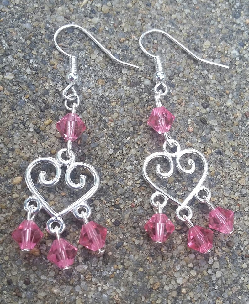 May include: Silver heart-shaped dangle earrings with pink crystal accents.
