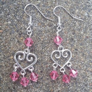 May include: Silver heart-shaped dangle earrings with pink crystal beads.