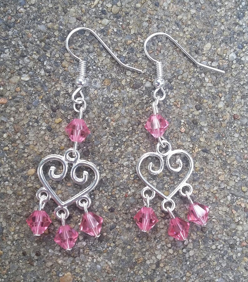May include: Silver heart-shaped dangle earrings with pink crystal beads.