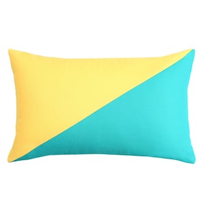 May include: A rectangular pillow with a diagonal color block design. The top left half is yellow, and the bottom right half is teal. The pillow is a solid color with no patterns or additional details.