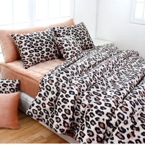 May include: A leopard print bedding set with a comforter, two standard pillows, and two throw pillows. The bedding is made of soft, plush fabric and features a bold leopard print in shades of brown, black, and white.