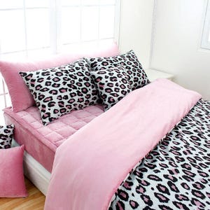 May include: Pink and white leopard print bedding with a pink velvet comforter and matching pillowcases.
