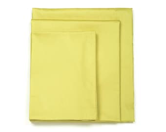 May include: Three yellow fabric pillowcases stacked on top of each other.