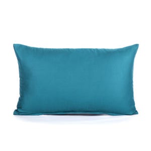 May include: A teal blue rectangular pillow with a smooth, solid surface.