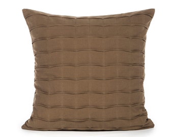 May include: A brown square pillow with a quilted design. The pillow is made of a soft, textured fabric.