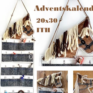 May include: A brown and white horse head advent calendar with 20 numbered pockets. The calendar is made of felt and has a brown and white yarn mane and tail. The text "Adventskalender 20x30 ITH" is printed on the top of the calendar.