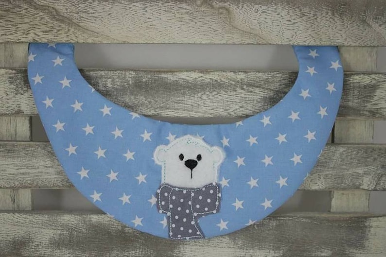 May include: A light blue baby bib with white stars and a white polar bear with a gray and white scarf.