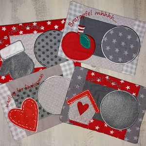 May include: Four gray and red fabric coasters with embroidered designs. The coasters feature a mitten, a heart, an apple, and a house. Each coaster has a gray circle in the center.