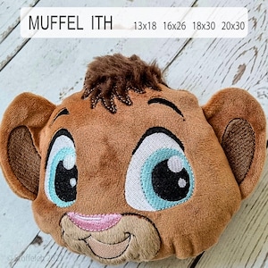 May include: Embroidered plush lion face with brown fur, large blue eyes, and a pink nose. The lion face is smiling and has a brown mane. The image includes the text "MUFFEL ITH" and sizes 13x18, 16x26, 18x30, and 20x30.