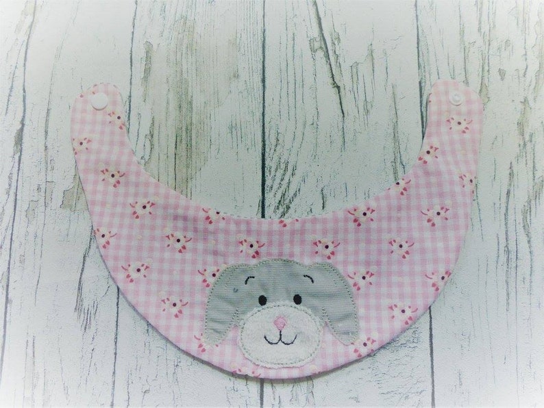 May include: Pink and white gingham baby bib with a gray felt puppy face applique.