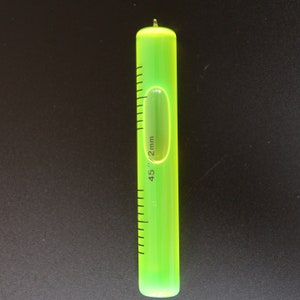 May include: A green level with a clear bubble and a black scale marked in millimetres. The level is 45 mm long.