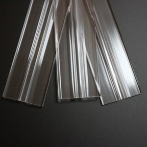 May include: Four clear plastic strips with a textured surface. The strips are arranged in a fan shape.