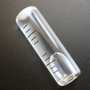 May include: A clear plastic tube with a graduated scale and a small bubble level inside. The tube is marked with "0.5 ml/2".