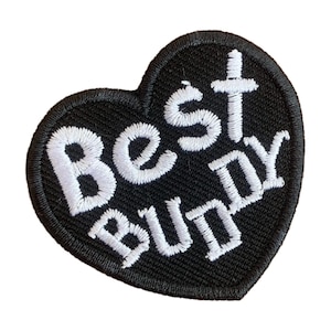 Può includere: Toppa a forma di cuore nera con testo ricamato bianco che recita "Best Buddy".