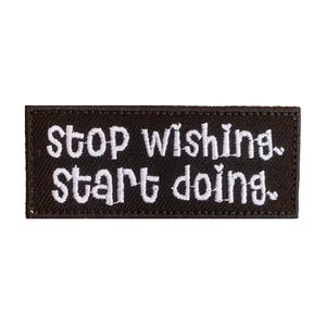 以下が含まれることがあります： 黒い刺繍パッチに白い文字で「stop wishing, start doing.」と書いてあります