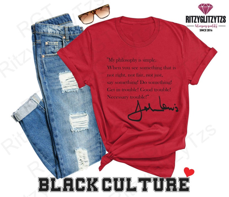 May include: A red t-shirt featuring a quote by John Lewis and his signature, alongside blue jeans and sunglasses. The shirt's text reads "My philosophy is simple..." and is part of a Black Culture collection.